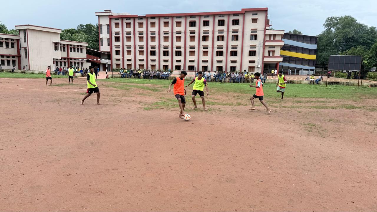 Students playing football on the school ground with the main building in the background